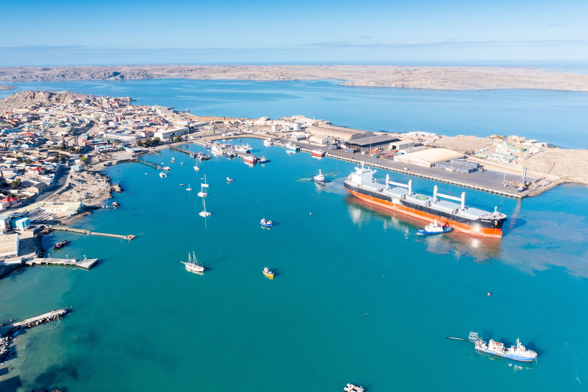 Freight vessel against backdrop of Luderitz, Namibia, medium wide